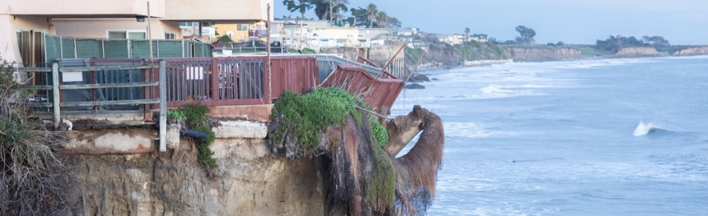 Coastal bluff collapse showing houses perched dangerously close to the cliff edge